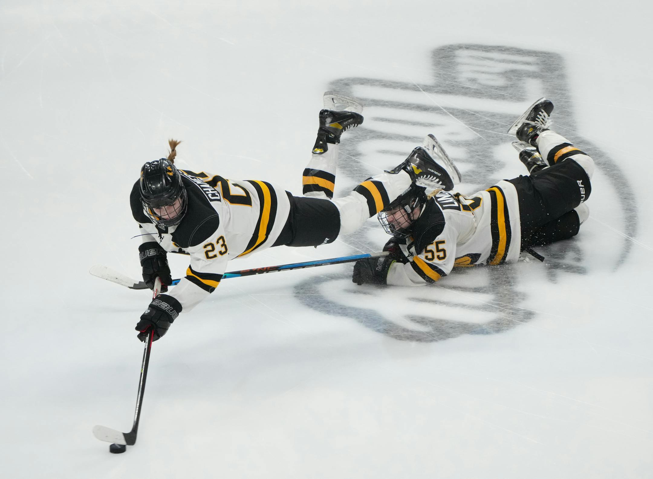 Warroad defenseman Abby Chamernick (23) keeps possession of the puck while midair after colliding with teammate forward Lila Lanctot (55) in the third period.