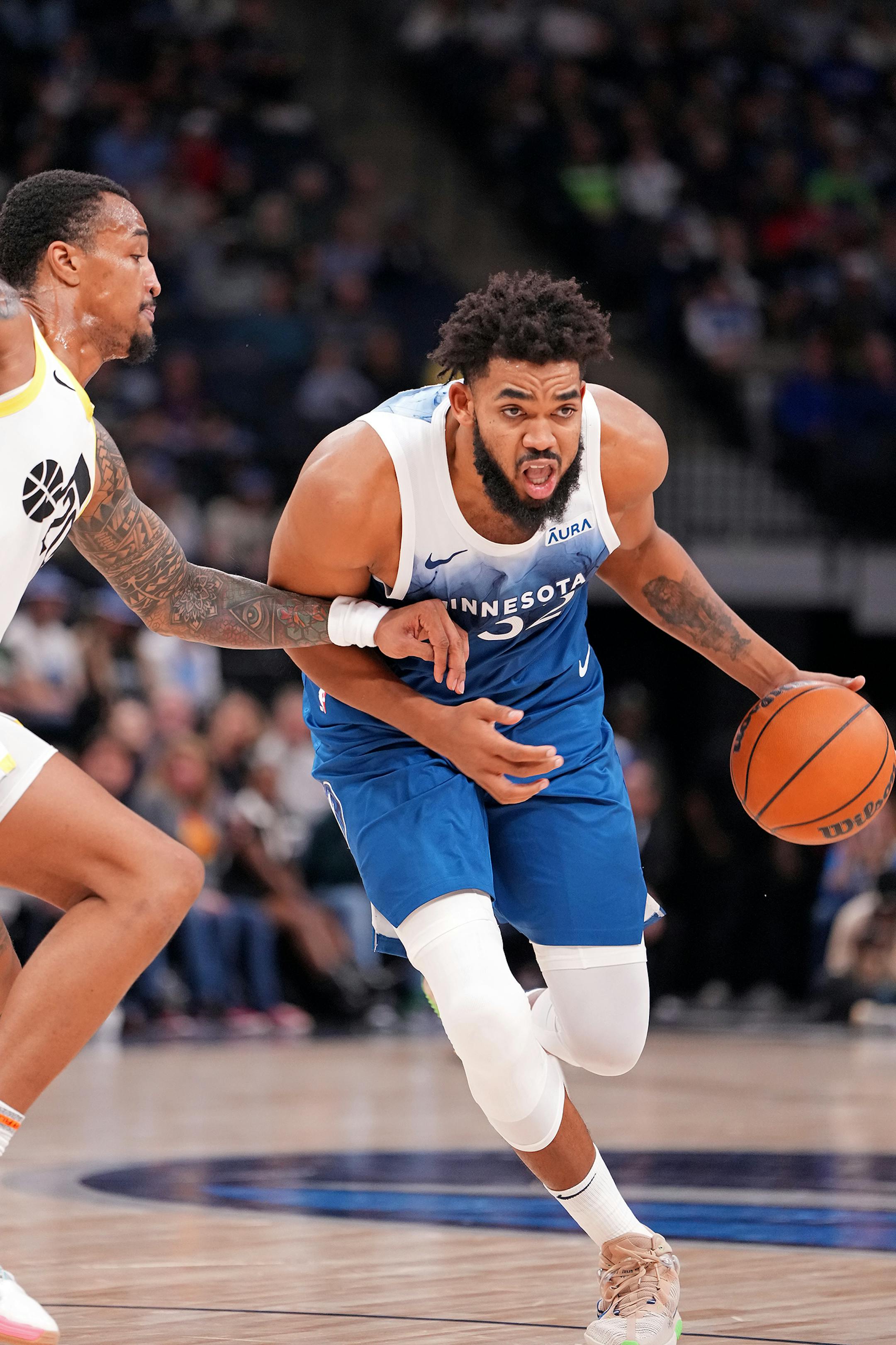 Minnesota Timberwolves center Karl-Anthony Towns (32) dribbles as Utah Jazz forward John Collins (20) defends during the second half of the game.