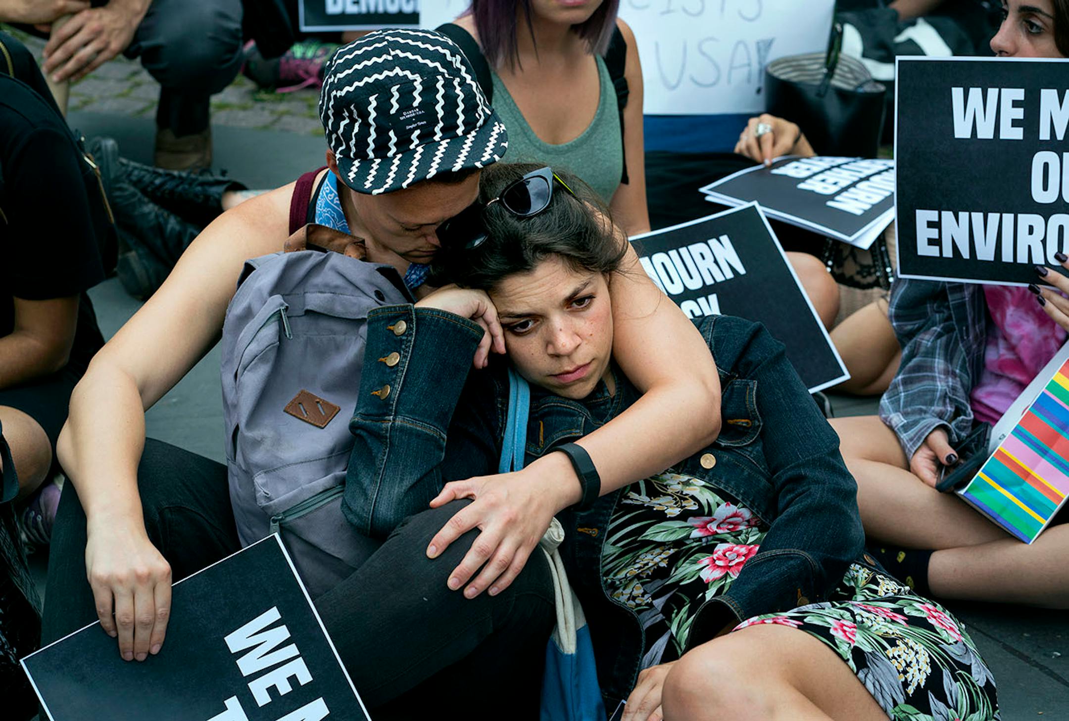 Protestors gathering at 59th Street and 5th Avenue in New York sit during a moment of silence Monday, Aug. 14, 2017, as they protest President Donald Trump not far from Trump Tower.