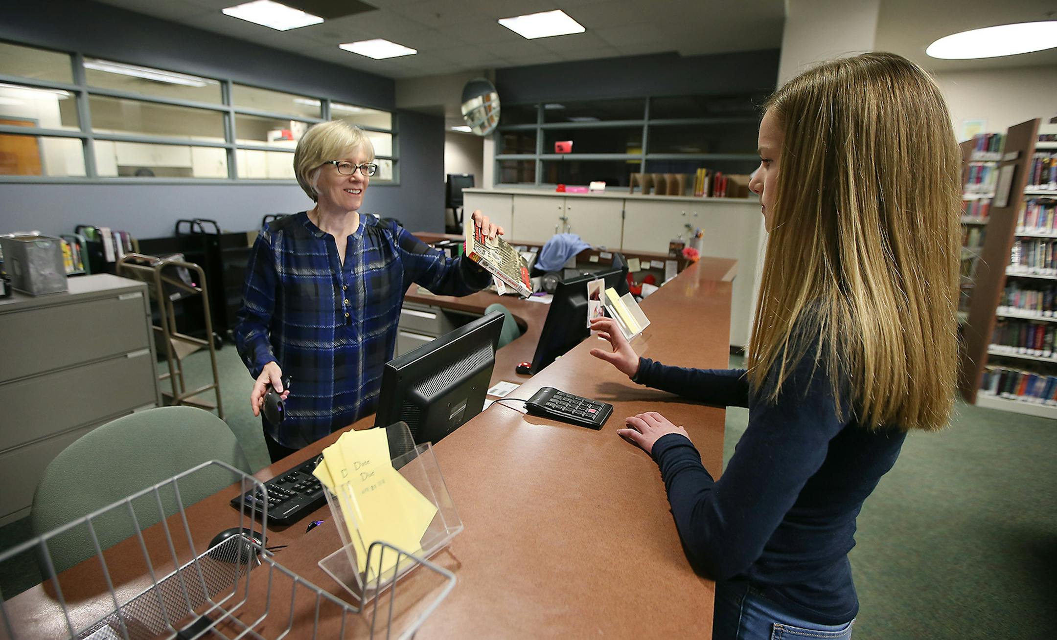 Central Middle School Media Clerk Elaine Duffy helped eighth-grader Mia Hood check out a book in the Media Center, Tuesday, April 12, 2016 in Eden Prairie, MN. ] (ELIZABETH FLORES/STAR TRIBUNE) ELIZABETH FLORES • eflores@startribune.com