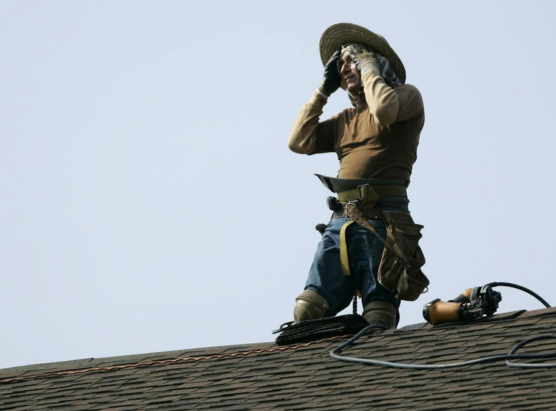 A construction worker wipes sweat from his face as he installs roofing tiles as part of a solar panel installation project at Park Ridge High School in Park Ridge, N.J., Wednesday, July 7, 2010. Temperatures in the Northeast are expected to reach 100 for the second straight day.