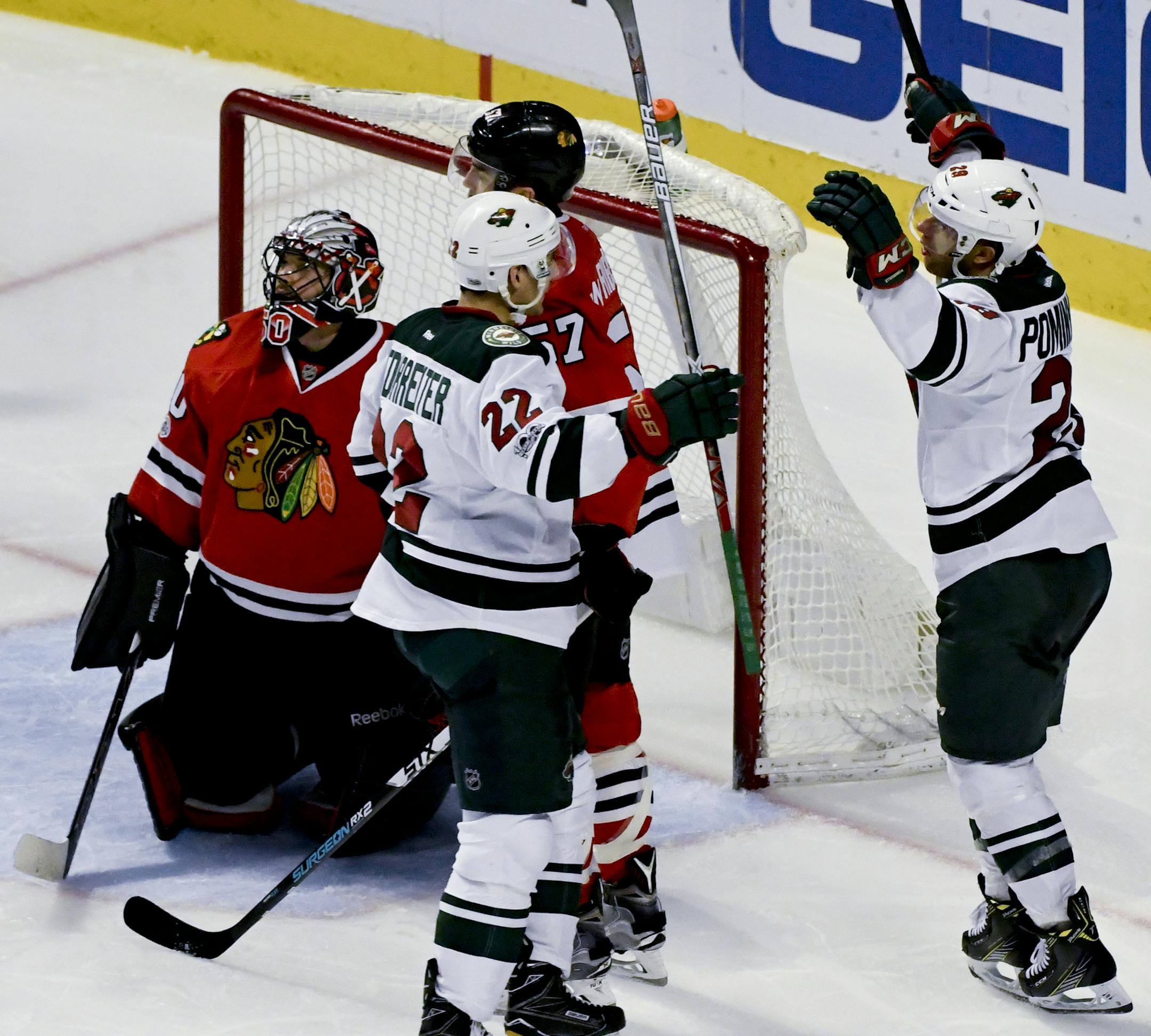 Chicago Blackhawks goalie Corey Crawford (50) and Trevor van Riemsdyk , center, look on as Minnesota Wild right wing Nino Niederreiter (22) and right wing Jason Pominville, right, celebrate after he scored the game winning goal during the third period of an NHL hockey game on Sunday, Jan. 15, 2017, in Chicago. (AP Photo/Matt Marton)