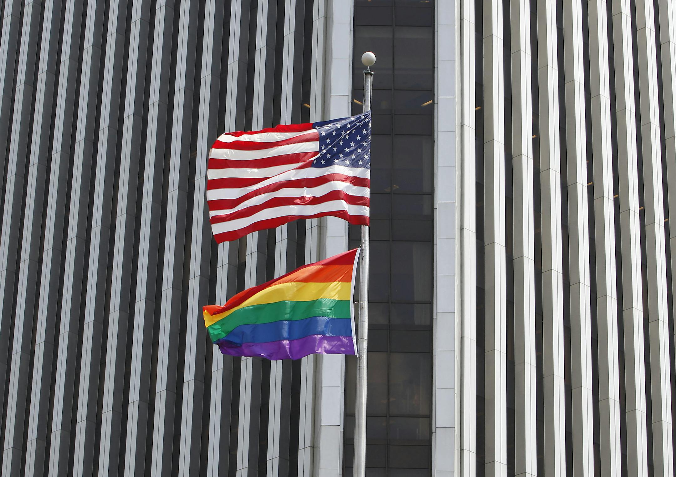 This Wednesday, June 1, 2011 picture shows U.S. and rainbow flags flying at the Federal Reserve Bank building in downtown Richmond, Va. Republican Del. Bob Marshall, Virginia's most outspoken legislative adversary of gay rights, has called out the president of the Federal Reserve Bank in Richmond for flying a gay-rights flag outside its downtown tower. Fed spokesman Jim Strader says the flag went up Wednesday at the request a gay, lesbian, bisexual and transgendered employees group called Prism