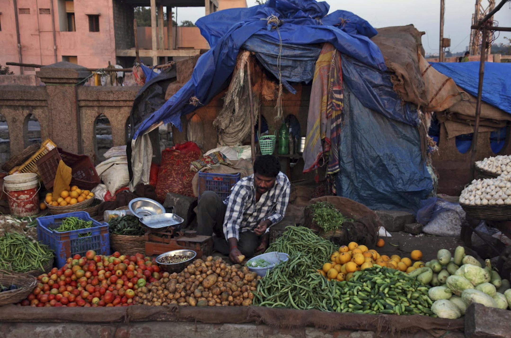 An Indian vendor sorts vegetables as he waits for customers in Hyderabad, India, Thursday, Jan. 2, 2014. The Indian rupee declined Thursday against the dollar amid demand from importers as the US currency strengthened overseas. (AP Photo/Mahesh Kumar A.)