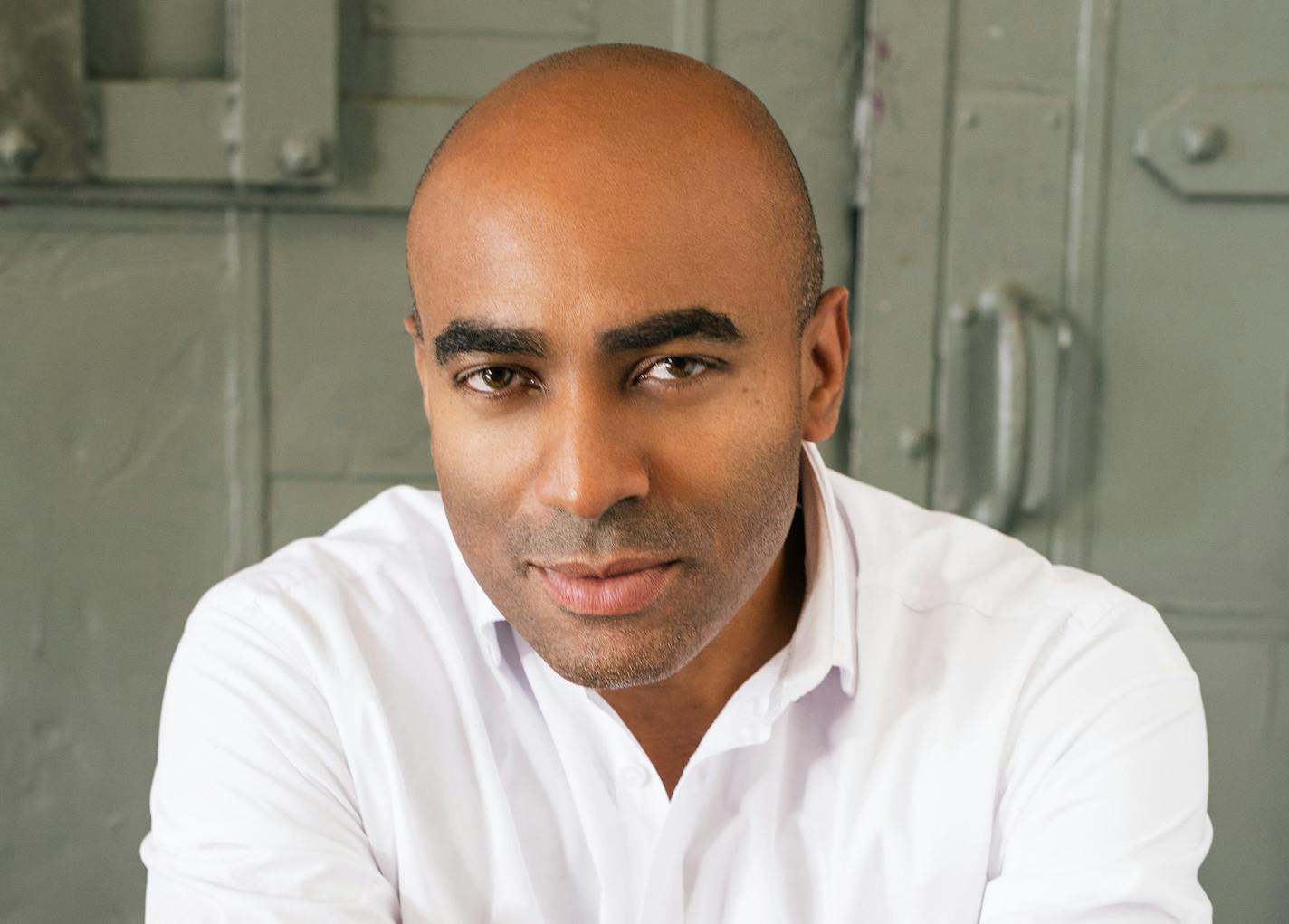 A headshot of an African American man in a white button down shirt