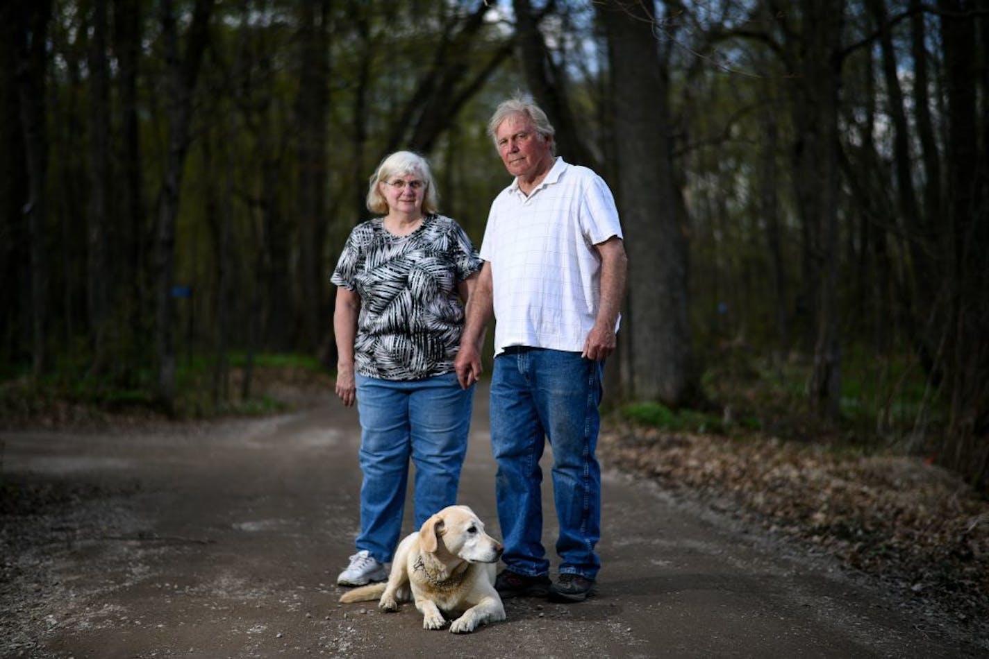 Kathy and Dwaine Ratfield and their 8-year old yellow lab, Dakota, stood for a portrait on the cartway path behind their home that is the focus of a 35-year battle with the local town board.