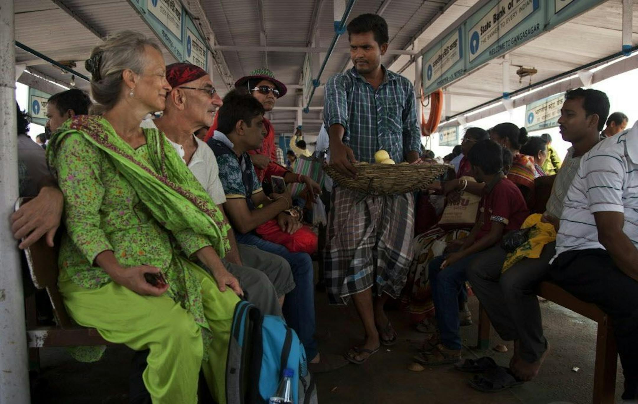 In this April 13, 2017 photo, Elizabeth Brenner, 62, in green dress, sits on a crowded steamer boat along with her partner Barry Knight near Gangasagar, West Bengal, India. Brenner's son died during a study abroad trip to the mountains of India more than five-years-ago. His body was never found. Brenner spent two months tracing the 1,037 mile path along the Ganges River to where it empties into the Bay of Bengal as she believes this is the path taken by her son's remains.
