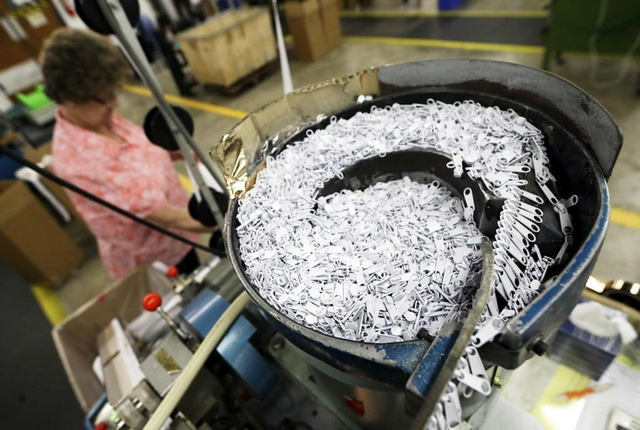 In this May 17, 2018, photo, Dee Ledford operates machinery that places zipper sliders onto zipper chains at the Dunlap Industries facility in Dunlap, Tenn. The small zipper-making company is fighting to keep its pared-down staff occupied after it lost federal contracts to provide zippers for military uniforms.