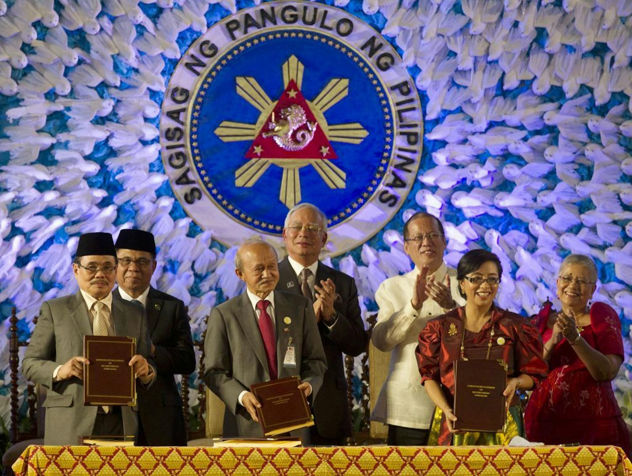 In this handout photo released by the Malacanang Photo Bureau, President Benigno S. Aquino III, second from right, applauds with Muslim leaders after the signing of the Comprehensive Agreement on the Bangsamoro (CAB), a peace agreement.