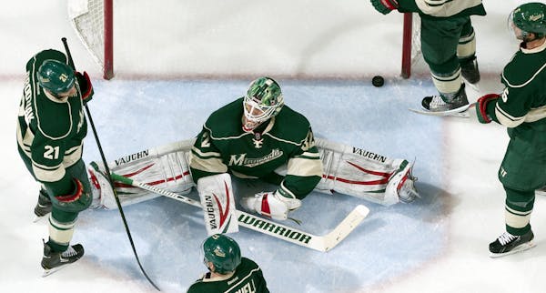 Wild goalie Niklas Backstrom (30) was surrounded by dejected teammates after a goal by Mikael Backlund (11) in the second period.