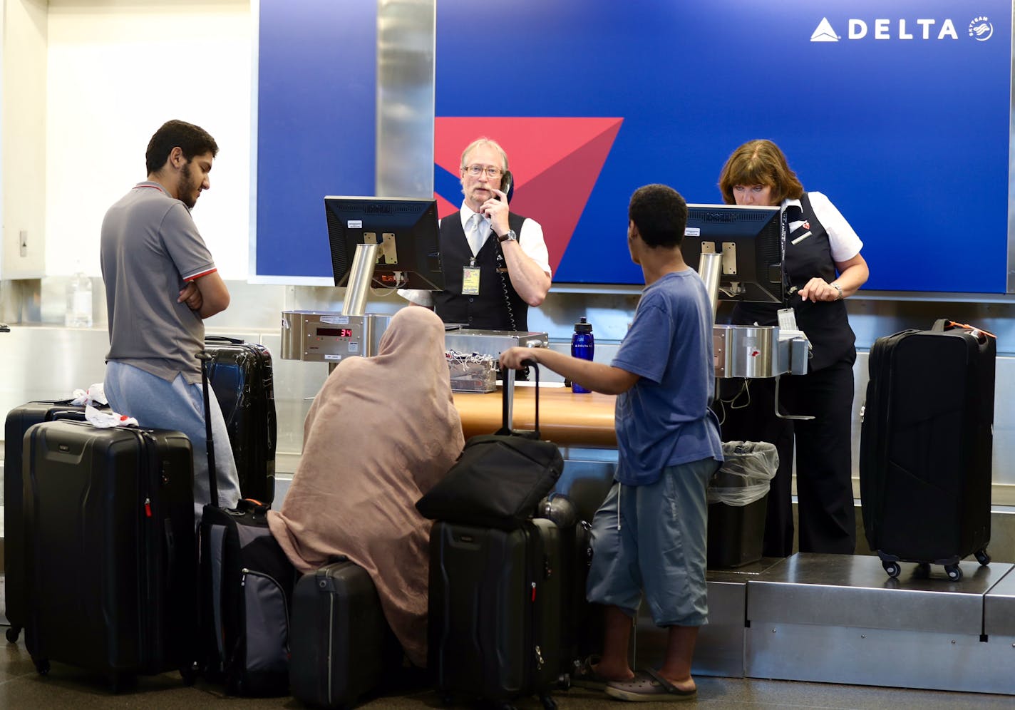 People wait with their baggage in the check-in area at Delta Air Lines counter in Terminal 1 of MSP Airport on Monday.