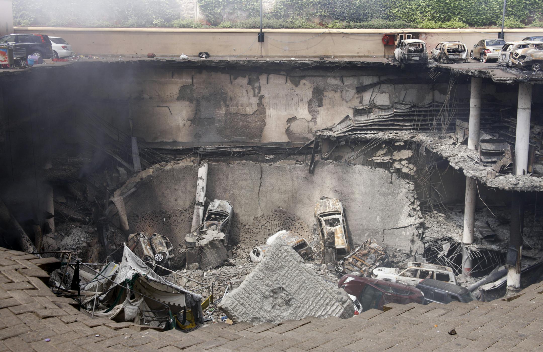 This photo released by the Kenya Presidency shows the collapsed upper car park of the Westgate Mall in Nairobi, Kenya Thursday, Sept. 26, 2013. Working near bodies crushed by rubble in a bullet-scarred, scorched mall, FBI agents continued fingerprint, DNA and ballistic analysis to help determine the identities and nationalities of victims and al-Shabab gunmen who attacked the shopping center, killing more than 60 people. (AP Photo/Kenya Presidency)