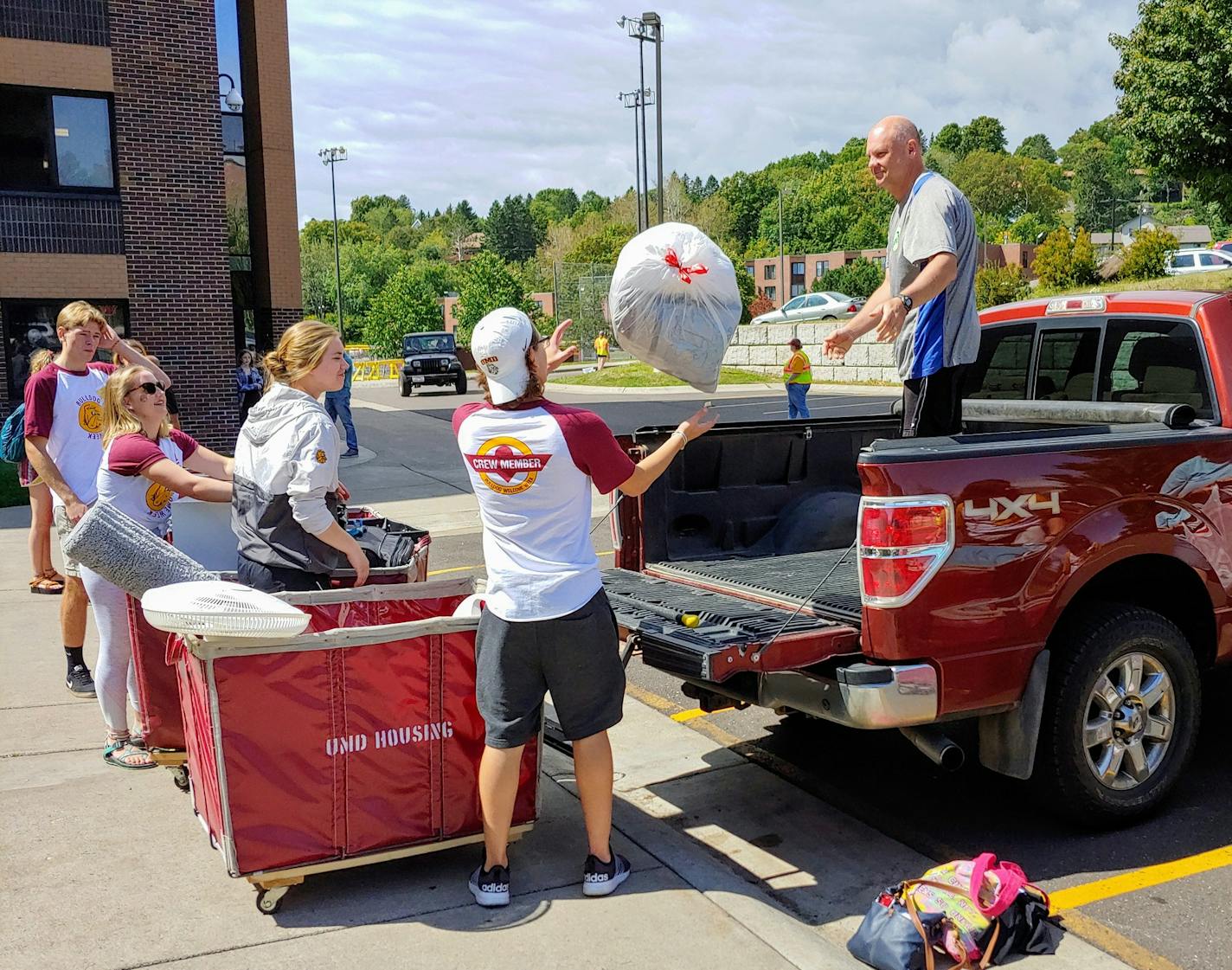 Mark Rahrick of Owatonna tosses some of his daughter Emily's belongings to a student volunteer during move-in day at the University of Minnesota Duluth in August. Brooks Johnson / Star Tribune