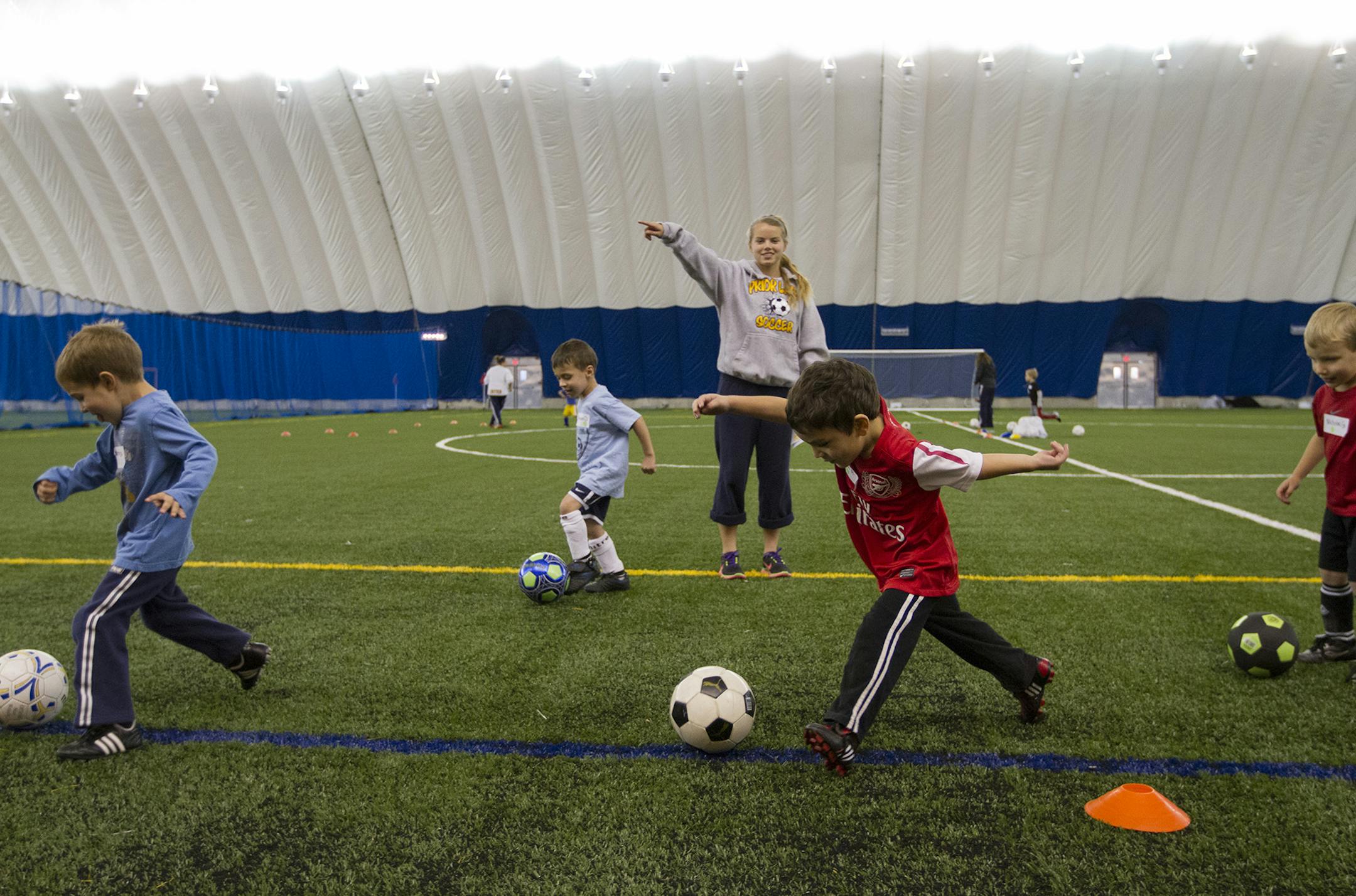 Coach Samantha Provost (cq/source), a junior at Prior Lake High School, instructed her group to dribble down the field towards a goal box. ] MARISA WOJCIK - Savage, Minnesota's new sports dome opened to the public for the first time on Thursday evening, November 1, 2012. The Prior Lake Soccer Club held soccer practice for it's three to five year olds in the dome's 104,000 square foot space. The facility is equipped with a turf field and batting cage. ORG XMIT: MIN1211012004015419