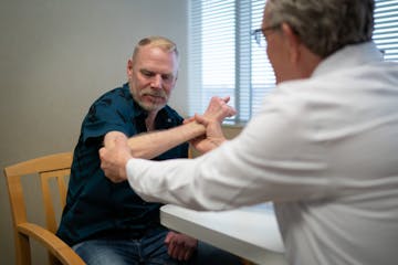 Dr. Allen Van Beek examined John Thompson’s arms at Van Beek’s Edina site in March. Thirty years ago, Van Beek reattached Thompson’s arms after 