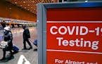 Travelers pass a sign near a COVID-19 testing site in Terminal E at Logan Airport, on Dec. 21, 2021, in Boston.