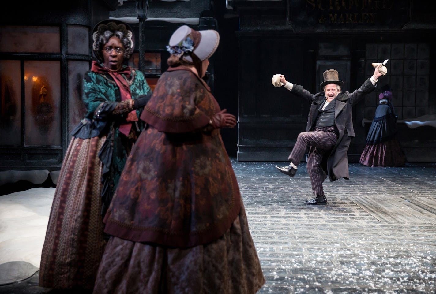 Isabell Monk O'Connor (Mrs. Dilber), Suzanne Warmanen (Bunty) and J.C. Cutler (Ebenezer Scrooge) in the Guthrie Theater's 41st annual production of the Charles Dickens classic, A Christmas Carol, adapted by Crispin Whittell and directed by Joe Chvala with set design by Walt Spangler, costume design by Mathew J. LeFebvre and lighting design by Christopher Akerlind. November 12 - December 27, 2015 on the Wurtele Thrust Stage at the Guthrie Theater, Minneapolis. Photo by Dan Norman.