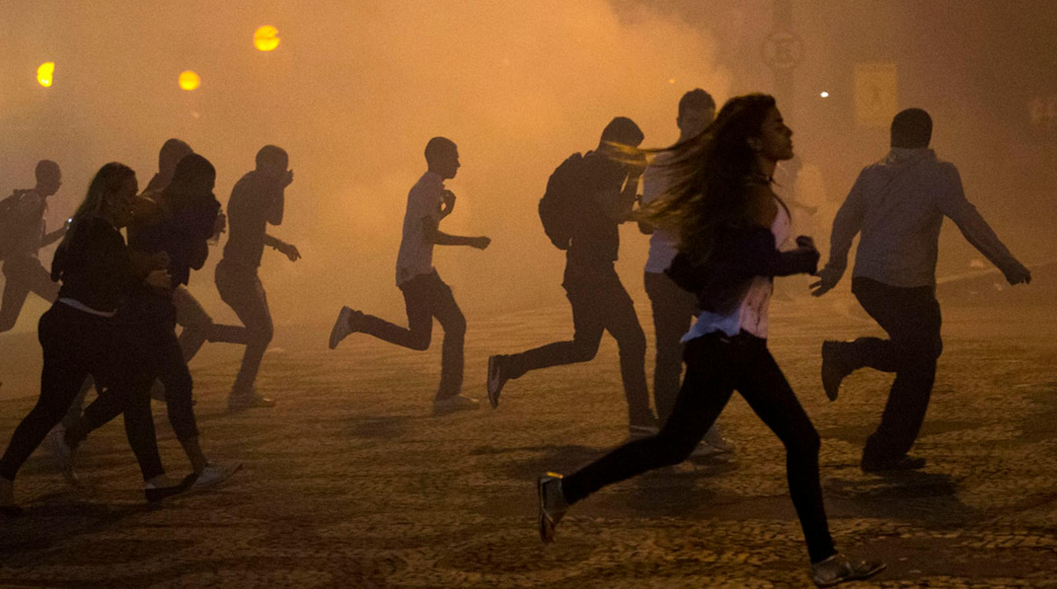 Protesters run from the clouds of tear gas during an anti-government protest in Rio de Janeiro, Brazil on June 20, 2013.