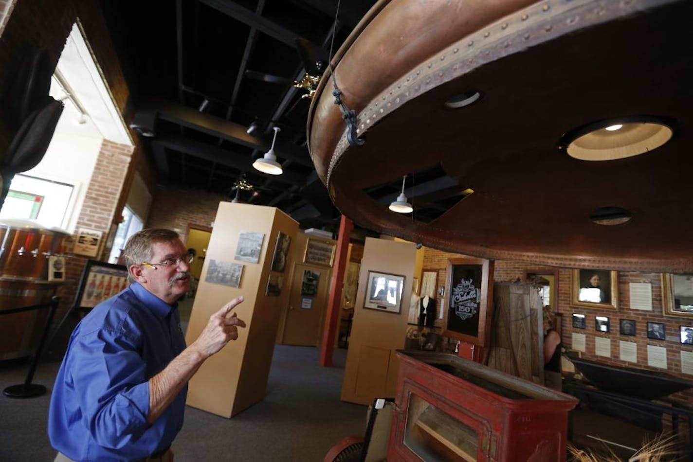 In New Ulm at the August Schell Brewery, Ted Marti is the fifth generation brewer. He is showing off a retired copper vat top in the brewery museum.