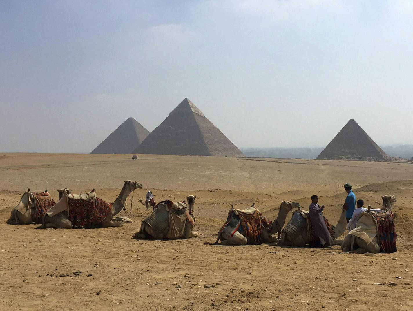 FILE - In this Aug. 30, 2015, file photo, camels rest between rides with their owners against the backdrop of the pyramids in Giza, Egypt. Archaeologists in Egypt say they have discovered a 4,400-year-old tomb near the pyramids outside Cairo. Egypt&#x2019;s Antiquities Ministry announced the discovery Saturday and said the tomb likely belonged to a high-ranking official known as Hetpet during the 5th Dynasty of ancient Egypt. (AP Photo/Courtney Bonnell, File)