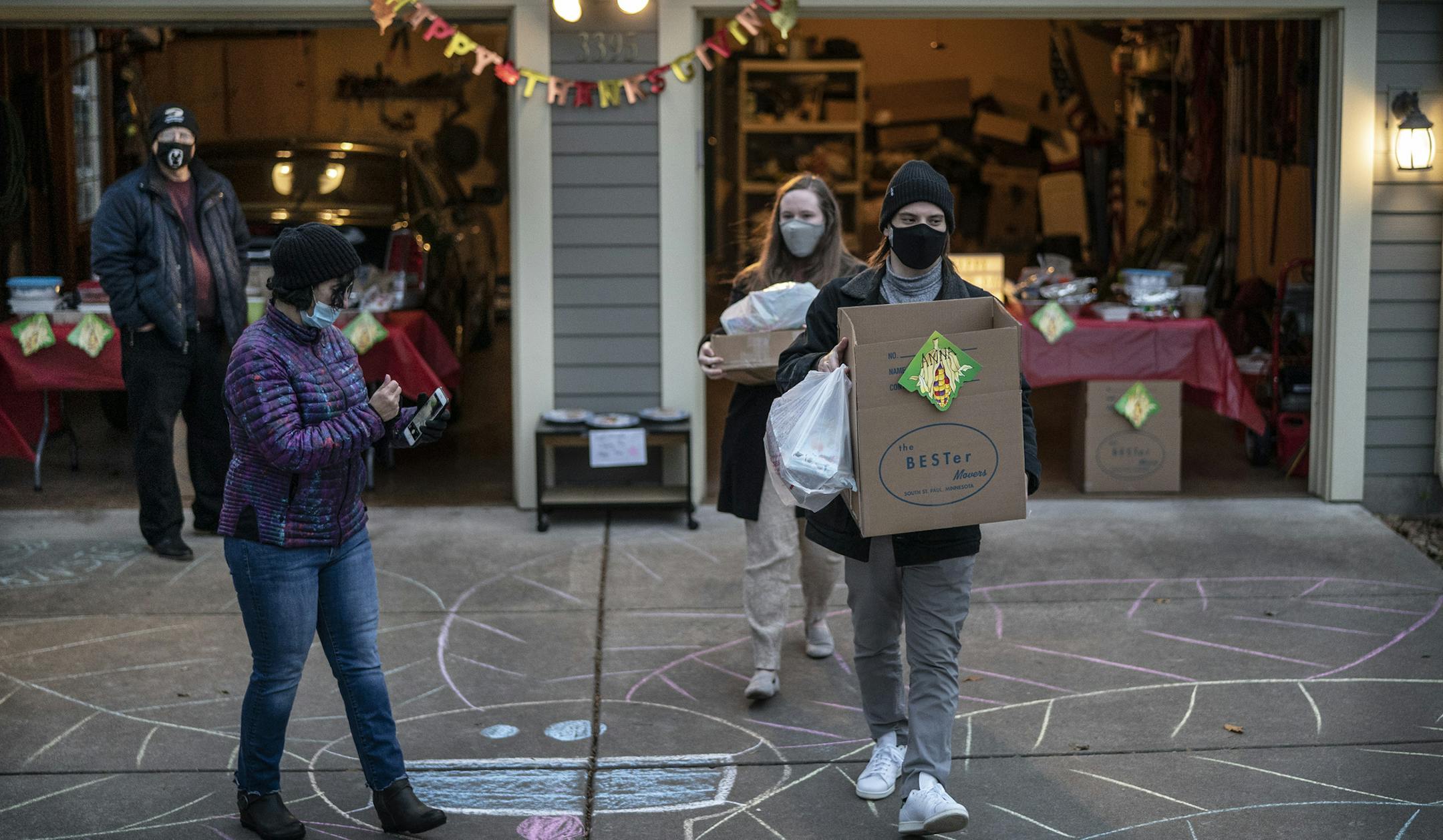 Jacob Bernstein and his wife, Anna Taddei, carried food from the home of Av Gordon. The family with a long tradition of big family get-togethers at Thanksgiving has hit on a safe way to mark the holiday this year — exchanging food with each other at a garage and taking it home to eat.