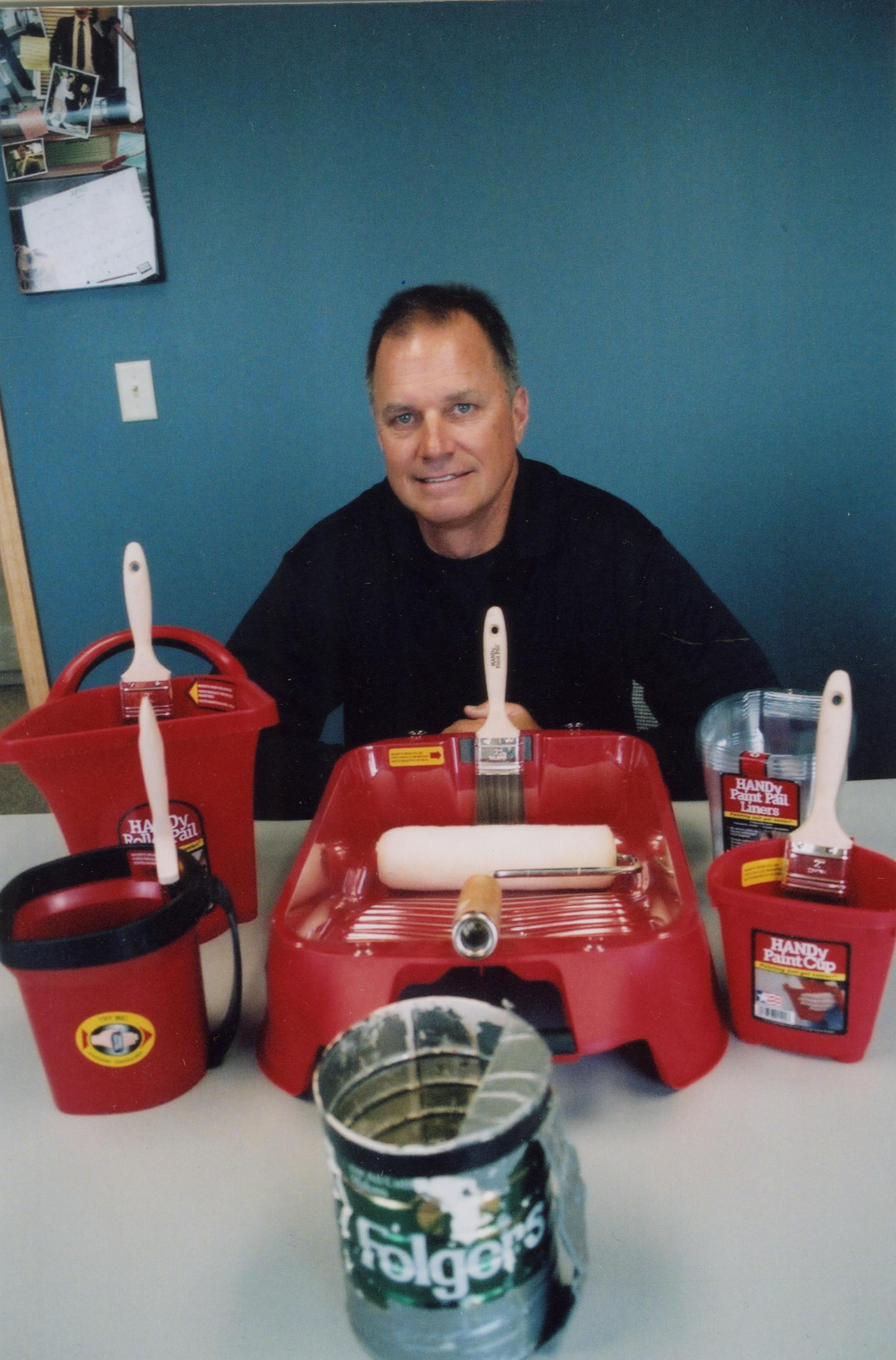 Mark Bergman, founder of Bercom International, is shown with his line of paint containers. Up front is the coffee can with the duct-tape handle that inspired the $6.5 million business.