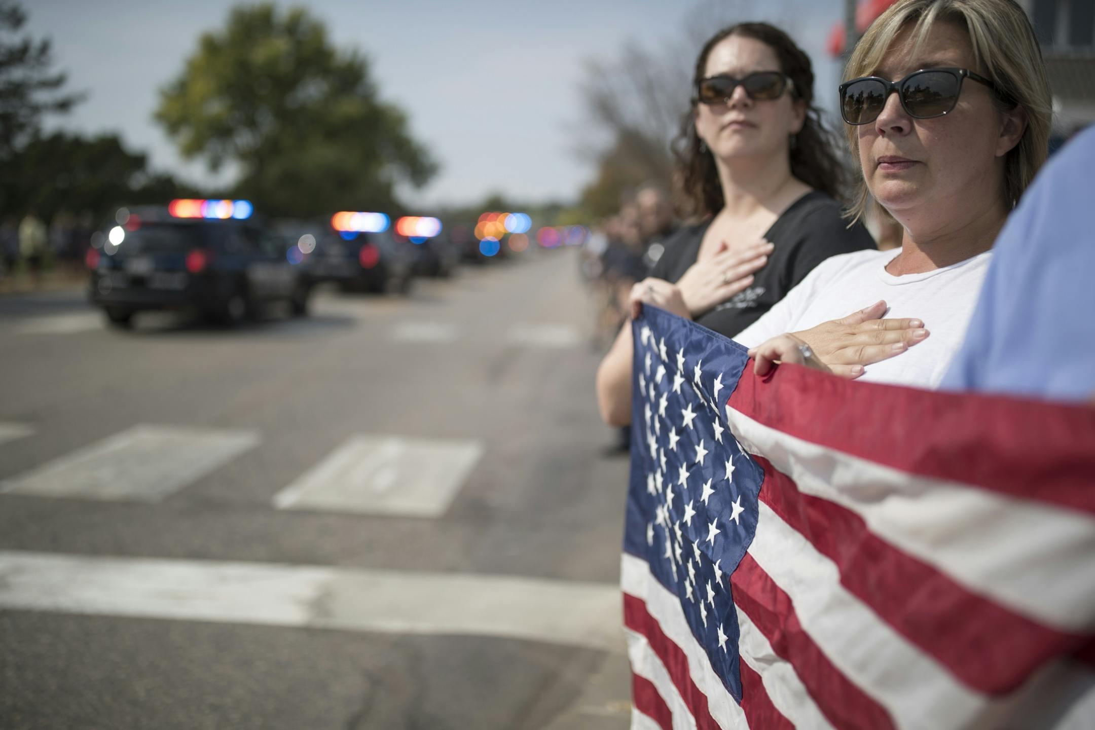 Kris Kovalik of Long Lake right ,and Kelly Zwilling of Mayer watched the funeral processions for Wayzata Police Officer Bill Mathews passed by Lake Minnetonka to Summit Park Cemetery were he will be buried Thursday September 14,2017 in Wayzata, MN.