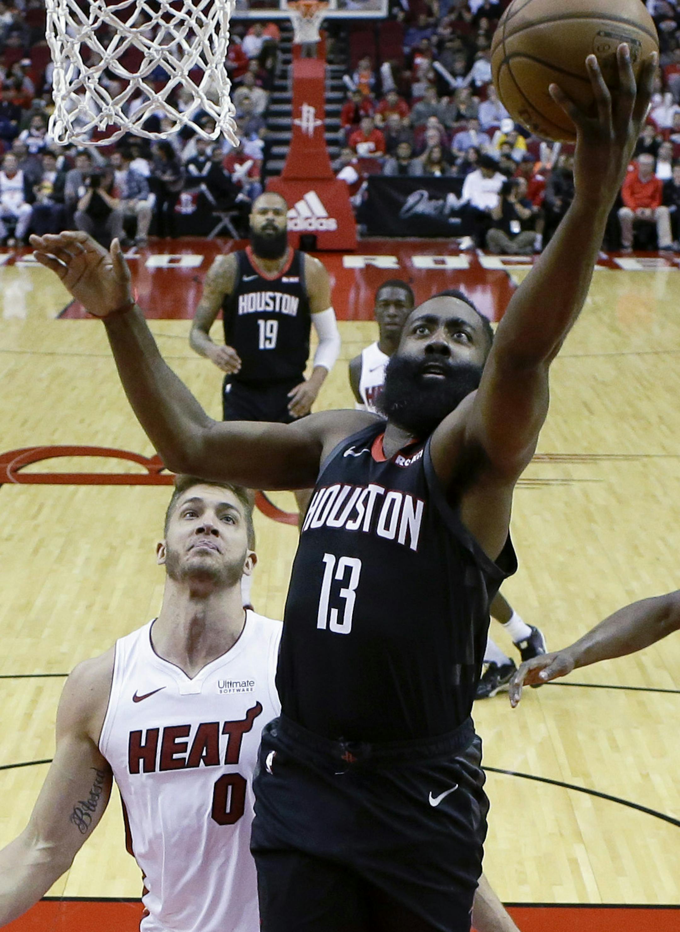 Houston Rockets guard James Harden (13) drives to the basket as past Miami Heat forward Meyers Leonard (0) and center Bam Adebayo (13) during the first half of an NBA basketball game, Wednesday, Nov. 27, 2019, in Houston. (AP Photo/Eric Christian Smith)