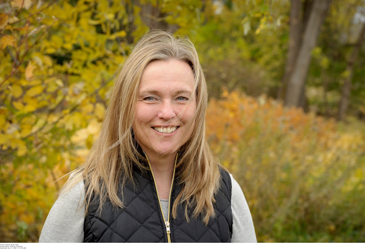 author Gretchen Anthony, standing near some woods