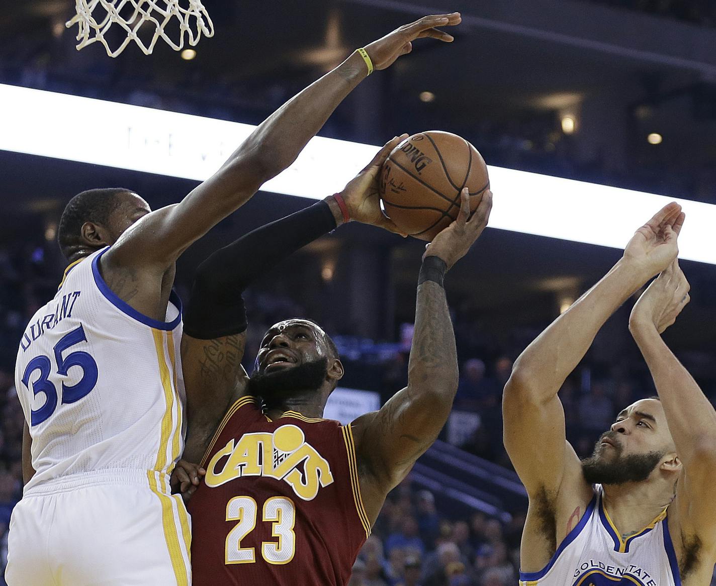 Cleveland Cavaliers' LeBron James, center, shoots between Golden State Warriors' Kevin Durant (35) and JaVale McGee, right, during the first half of an NBA basketball game Monday, Jan. 16, 2017, in Oakland, Calif. (AP Photo/Ben Margot)