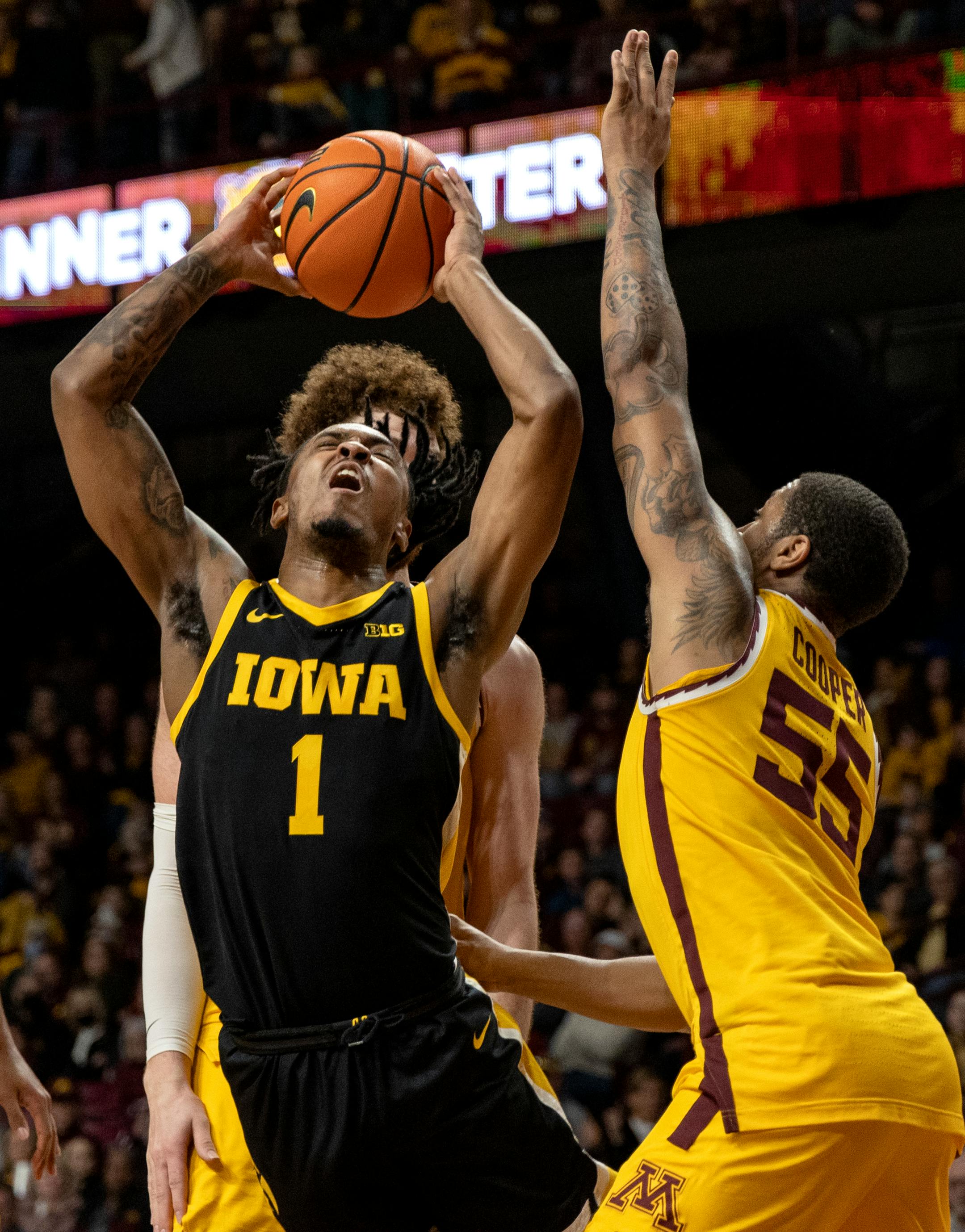 Ahron Ulis (1) of the Iowa Hawkeyes is defended by Ta'Lon Cooper (55) of the Minnesota Gophers in the second half.