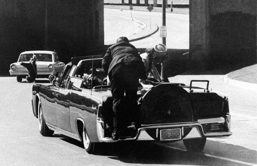 FILE - In this Nov. 22, 1963 file photo, President John F. Kennedy slumps down in the back seat of the Presidential limousine as it speeds along Elm Street toward the Stemmons Freeway overpass after being fatally shot in Dallas. Mrs. Jacqueline Kennedy leans over the president as Secret Service agent Clinton Hill rides on the back of the car. (AP Photo/Ike Altgens, File) ORG XMIT: TXKJ307