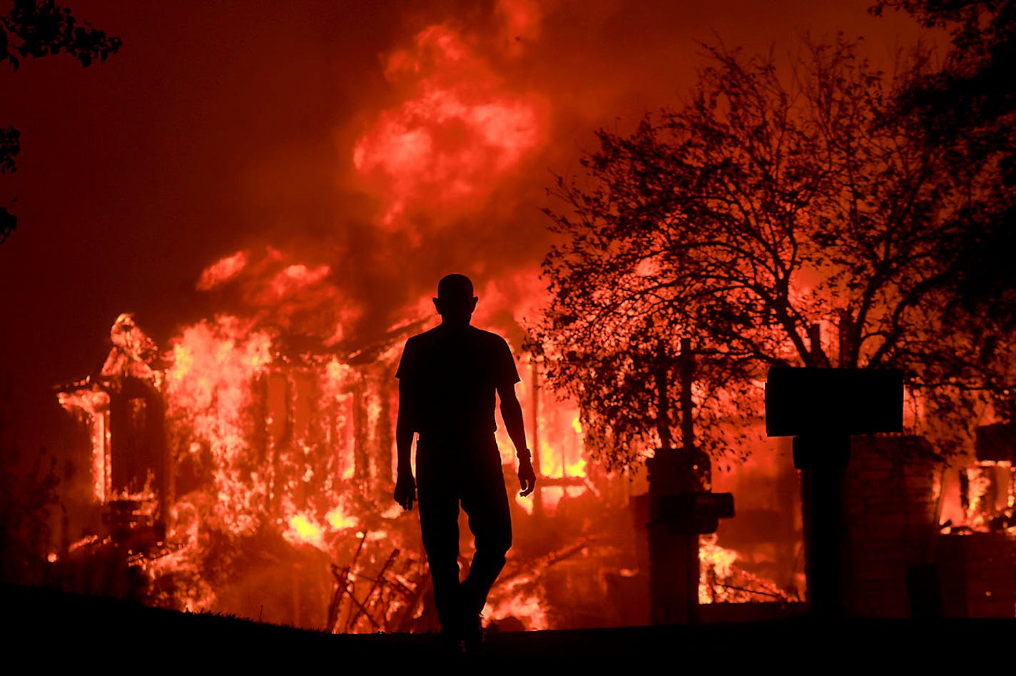 Jim Stites watches part of his neighborhood burn in Fountaingrove, Calif., Monday Oct. 9, 2017. More than a dozen wildfires whipped by powerful winds been burning though California wine country. The flames have destroyed at least 1,500 homes and businesses and sent thousands of people fleeing. (Kent Porter/The Press Democrat via AP)