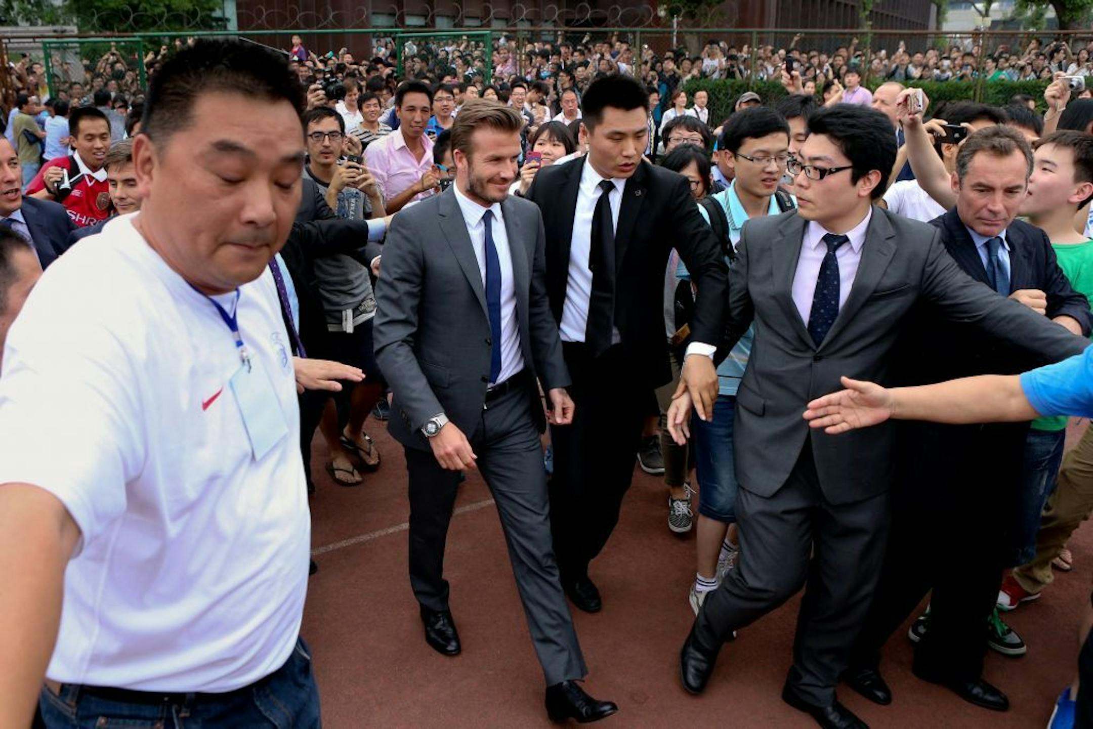 David Beckham walks to meet his fans before a stampede caused by fans storming a security cordon in a university in Shanghai Thursday June 20, 2013. Fans eager to see the soccer superstar stormed a police cordon in a stampede that injured seven people including five security personnel. (AP Photo) CHINA OUT