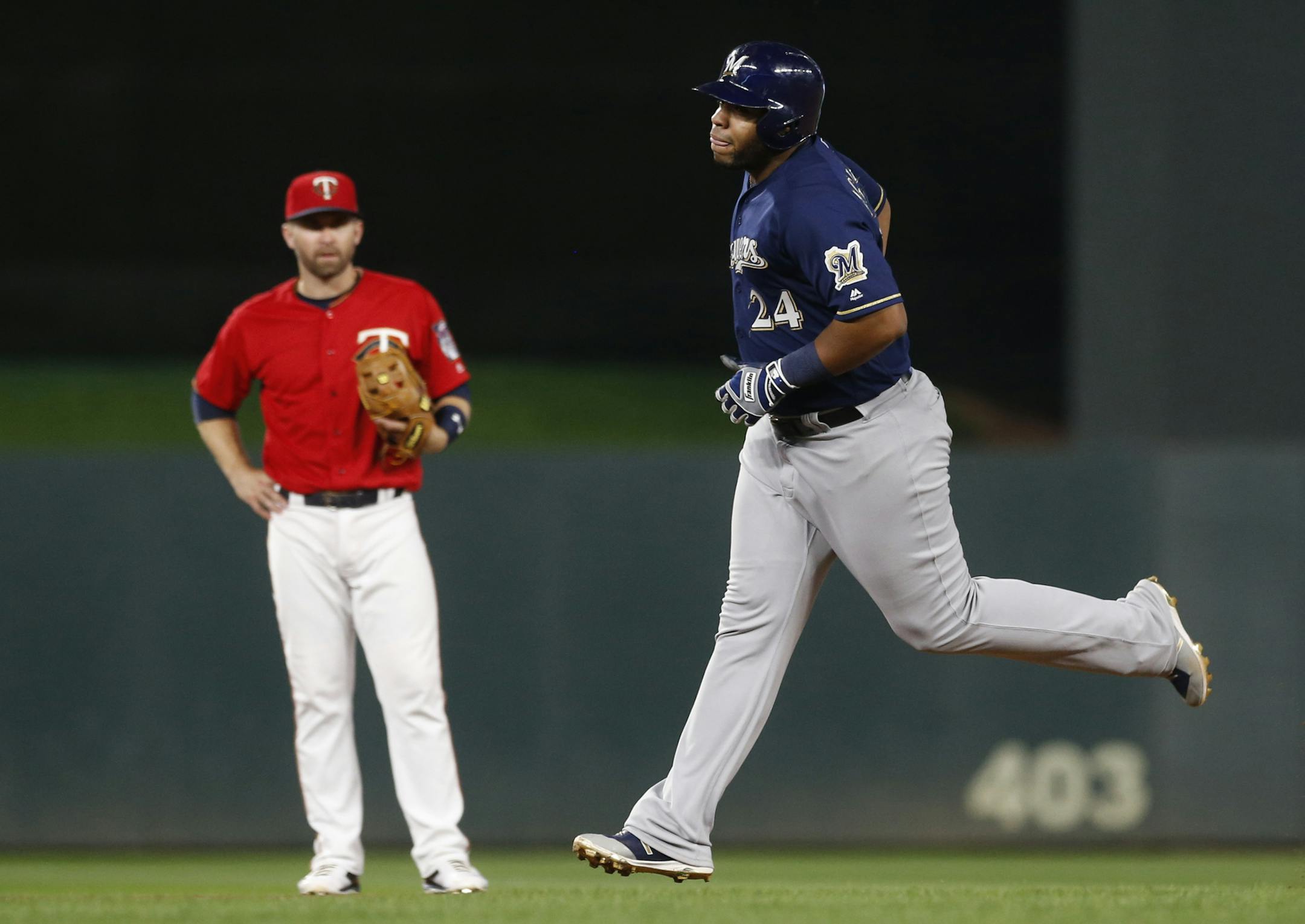 Milwaukee Brewers' Jesus Aguilar, right, rounds the bases on a solo home run as Minnesota Twins' second baseman Brian Dozier watches in the seventh inning of a baseball game Friday, May 18, 2018, in Minneapolis. (AP Photo/Jim Mone)