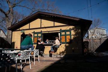 Bud Burge (in window) turned his Uptown garage into his Garage Bar. He and his wife, Sallie Watson Burge, right, hosted friends for a happy hour.