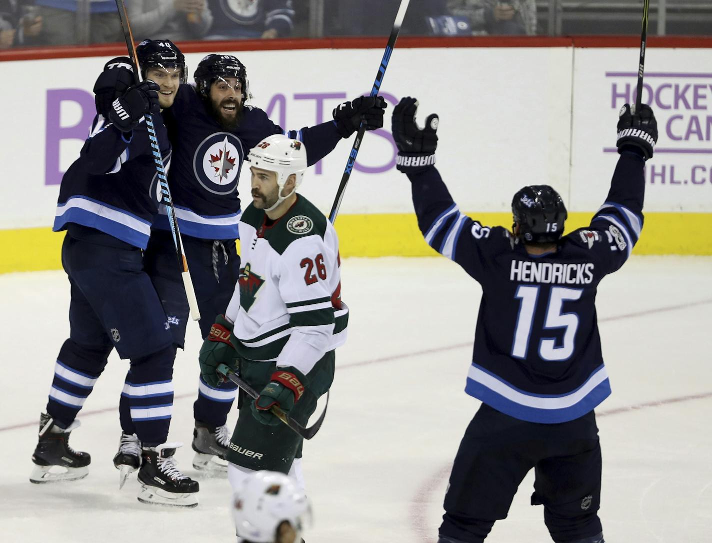 Winnipeg Jets' Joel Armia (40), Mathieu Perreault (85) and Matt Hendricks (15) celebrate after Armia scored as Minnesota Wild's Daniel Winnik (26) looks on during the first period of an NHL hockey game in Winnipeg, Monday, Nov. 27, 2017. (Trevor Hagan/The Canadian Press via AP)