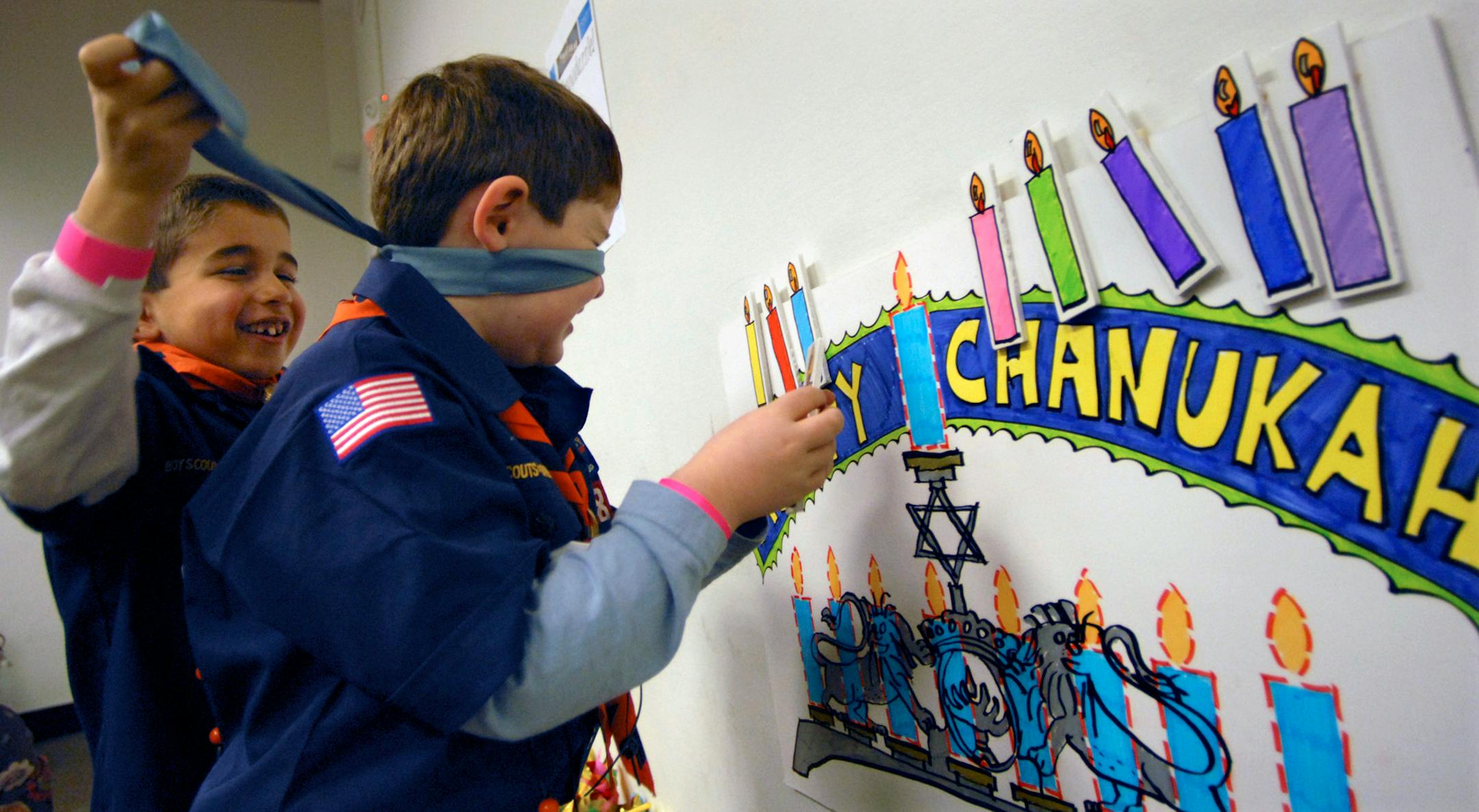 Max Ferstan, 6, blindfolded fellow Cub Scout, Ethan Kahn, 7, as he took a turn at "Pin-the-Candle-on-the-Menorah," one of the games at Sabes Jewish Community Center's "Chanudazzle" celebration.