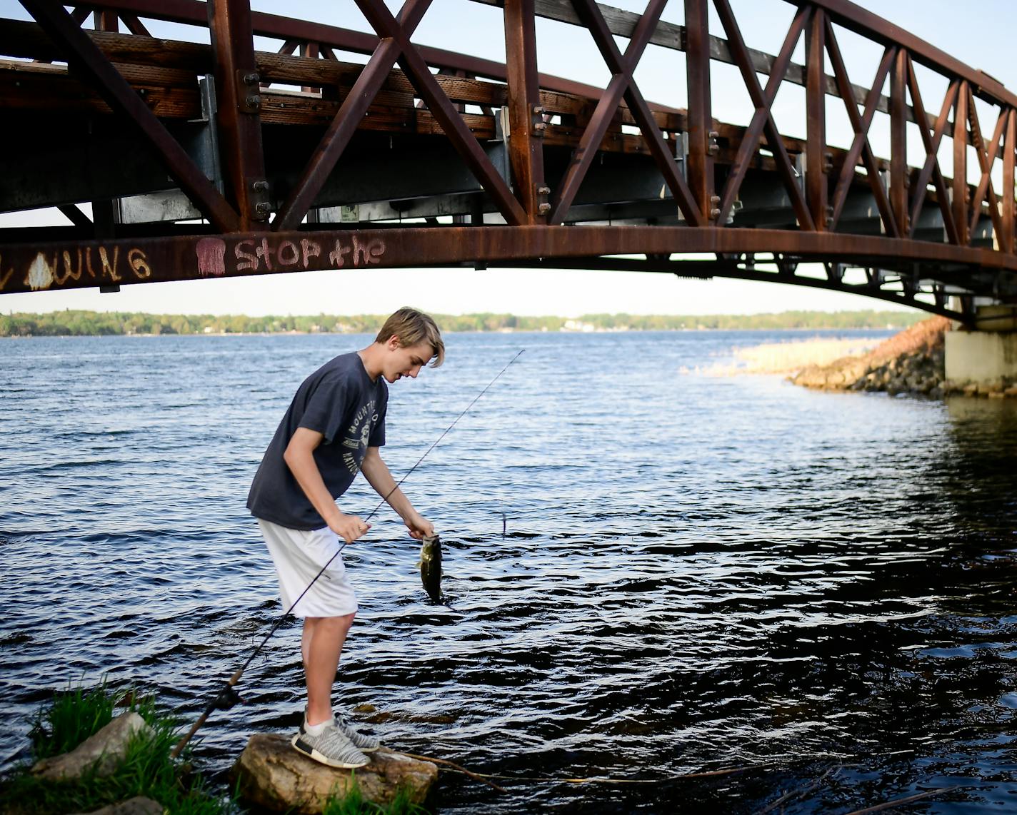 Anthony Brooks, a freshman at White Bear high's north campus, released a large mouth bass he caught while fishing White Bear Lake Thursday. ] AARON LAVINSKY &#xef; aaron.lavinsky@startribune.com Cities across the east metro are fighting efforts to rein in their groundwater use stemming from a lawsuit over White Bear Lake. About a dozen communities are challenging Department of Natural Resources orders to they impose residential irrigation plans during certain periods and develop plans to switch