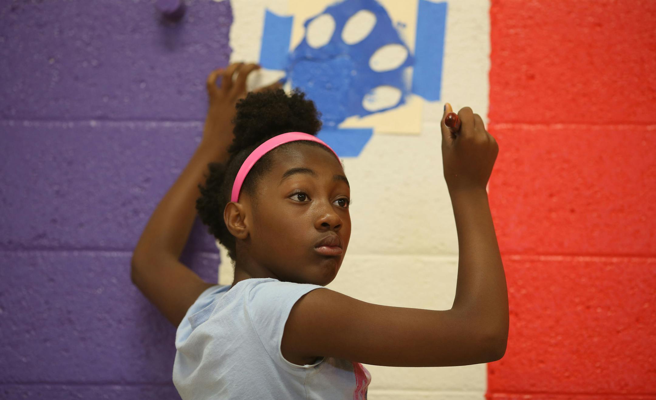 Jamiah Ward, 10, who will be a fifth grader this year, filled in a stencil paw print that adorned the walls in the gym. ] (KYNDELL HARKNESS/STAR TRIBUNE) kyndell.harkness@startribune.com During a day of "beautification" at Northport Elementary School in Brooklyn Park, Min., Tuesday, August, 19, 2014.