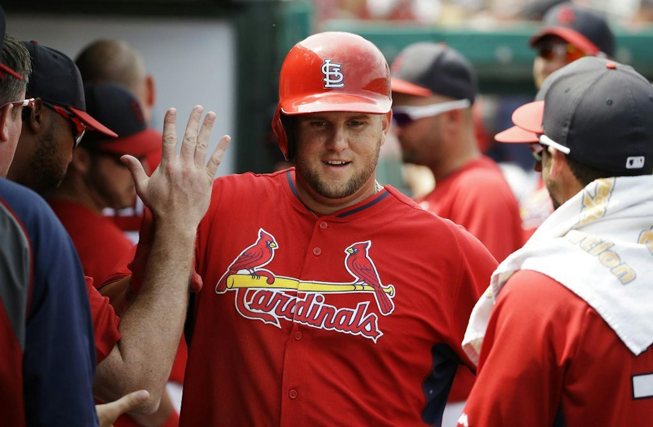 St. Louis Cardinals' Matt Adams high-fives teammates after hitting a home run in the fifth inning of an exhibition spring training baseball game against the Minnesota Twins, Wednesday, March 19, 2014, in Jupiter, Fla.