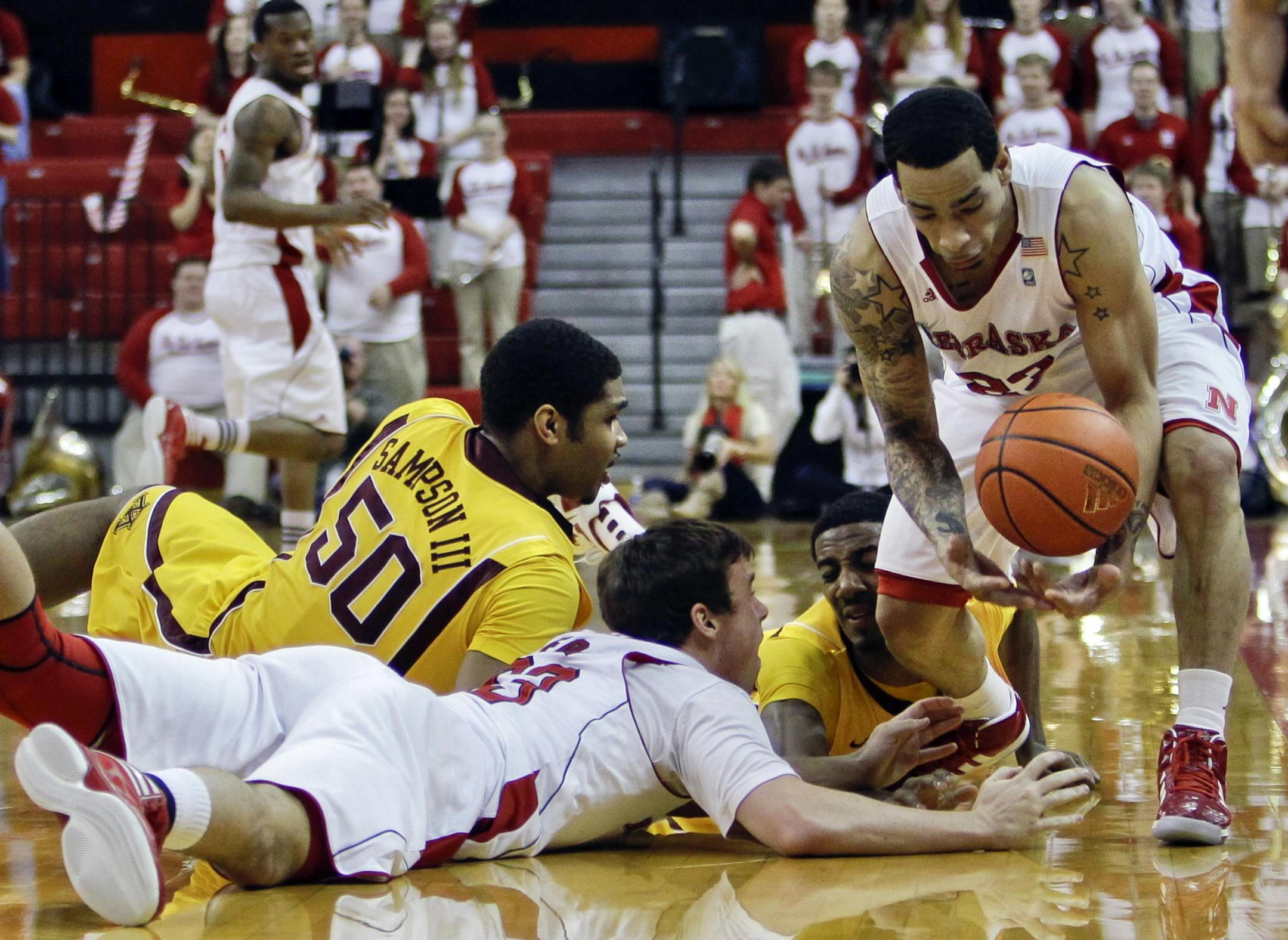 Minnesota's Ralph Sampson III (50) and Austin Hollins, rear, scramble for a loose ball against Nebraska's Mike Fox, front, and Bo Spencer, right, in the first half of their NCAA college basketball game in Lincoln, Neb., Sunday, Feb. 5, 2012.
