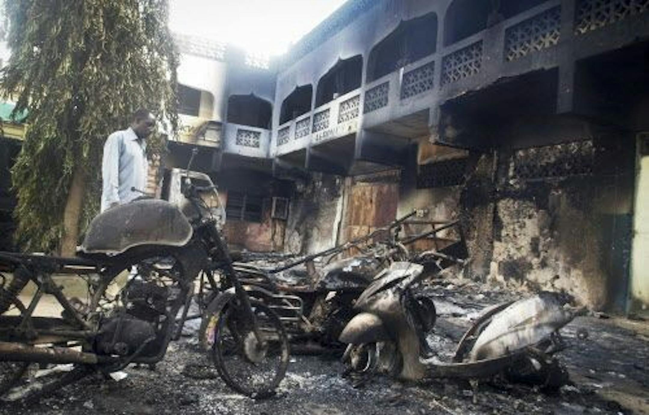 A man observes the remains of destroyed vehicles and buildings in the town of Mpeketoni, about 60 miles (100 kilometers) from the Somali border on the coast of Kenya Monday, June 16, 2014.