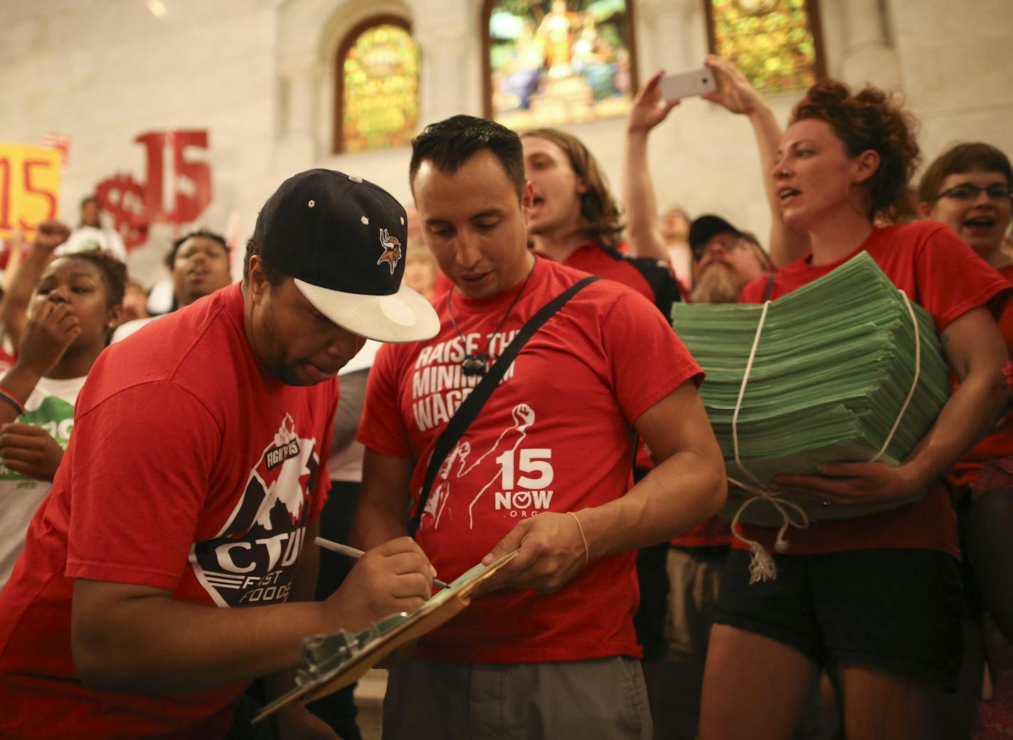 While Steven Suffridge signed the petition to be the 20,001st supporter, Ginger Jentzen held the stack of signed petitions in support of a $15 minimum wage as demonstrators rallied in City Hall and heard speeches before handing over a petition with 20,000 signatures on it to the City Clerk. ] JEFF WHEELER &#xef; jeff.wheeler@startribune.com Supporters of an $15 minimum wage amendment to the Minneapolis City Charter rallied at City Hall before presenting the City Clerk with a petition signed by 2