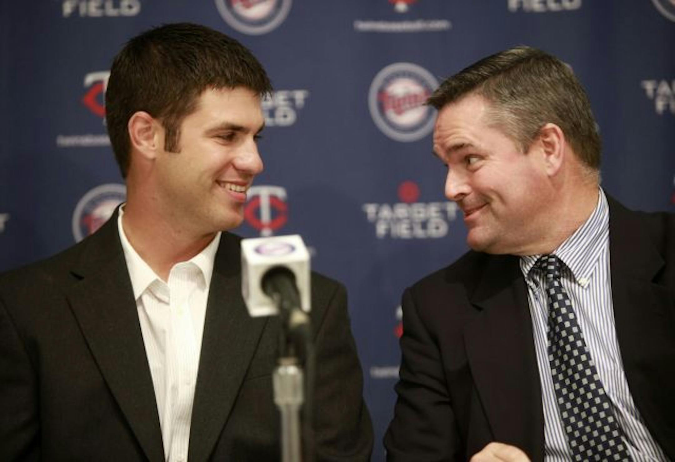 Minnesota Twins catcher Joe Mauer, left, and Twins general manager Bill Smith, right, talk before the start of a news conference at the team's training facility in Fort Myers, Fla., Monday, March 22, 2010. Mauer agreed to an eight-year, $184 million contract extension to stay with the Twins.