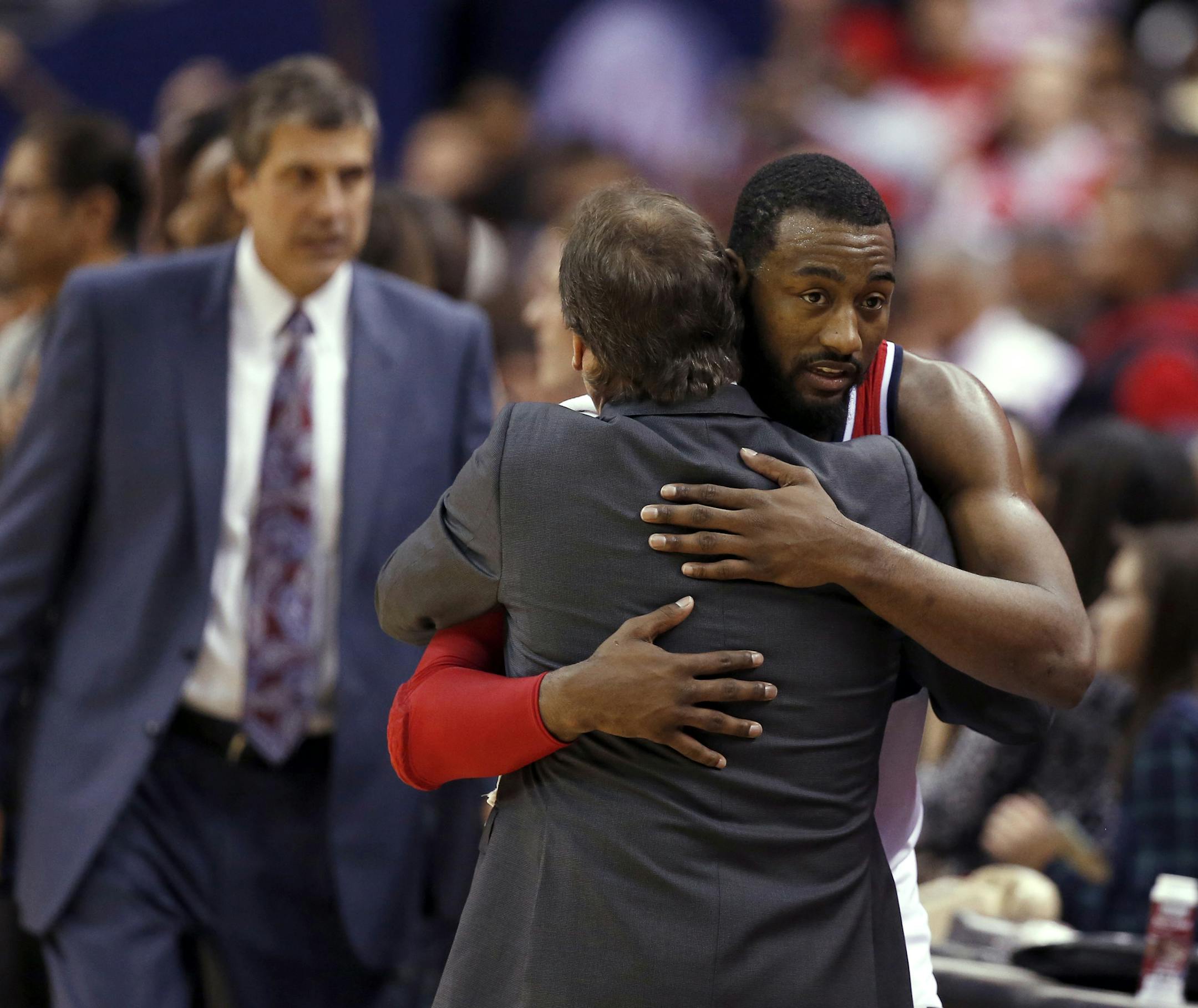 Washington Wizards guard John Wall embraces Minnesota Timberwolves coach Flip Saunders, with Wizards coach Randy Wittman, back left, after an NBA basketball game, Tuesday, Dec. 16, 2014, in Washington. The Wizards won 109-95. (AP Photo/Alex Brandon)