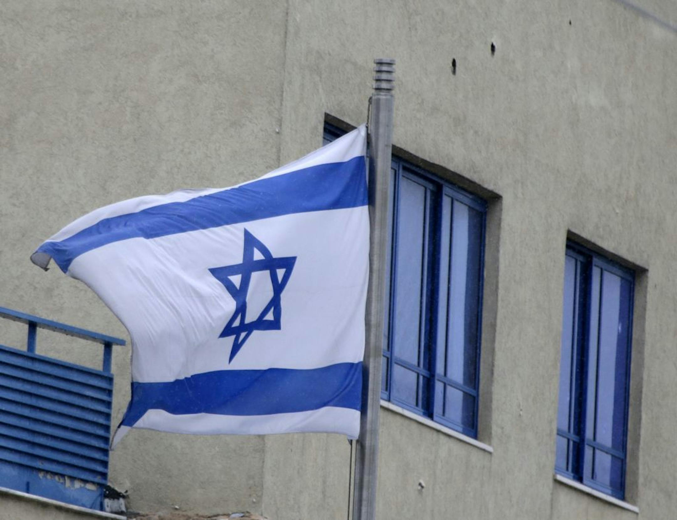Bullet holes are seen on the wall of Israeli Embassy after a pre-dawn gunfire attack in Athens, Friday, Dec. 12, 2014. Greek authorities are investigating the pre-dawn, drive-by gunfire attack on the Israeli embassy and officials said at least 20 bullet casings were found near the scene of the attack, which occurred long before the building opened for business.
