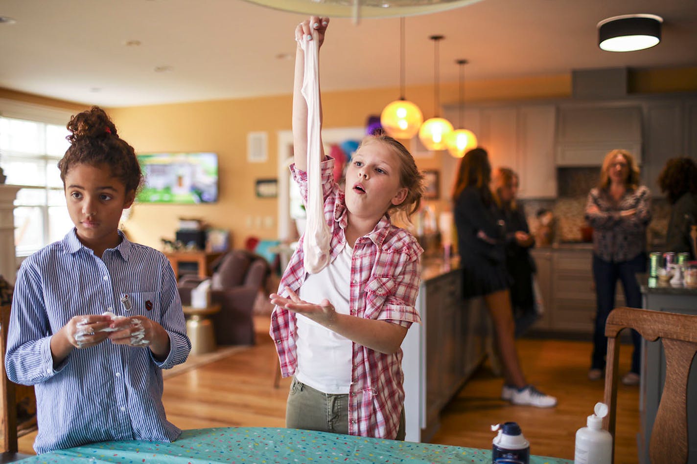 Gigi Shapiro, 12, let her batch of slime stretch while Catherine Walker, 9, kneaded a small batch as the moms visited in the kitchen nearby.