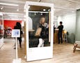 Gabriella Massey, a junior interior designer with Bailey Edward, takes a peek at a phone booth by ROOM on the 7th floor at NeoCon being held at the Me
