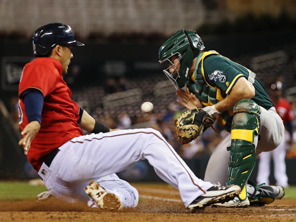 The Twins' Kurt Suzuki scored before Oakland catcher Matt McBride could apply the tag in the fourth inning of Minnesota's 11-4 victory at Target Field